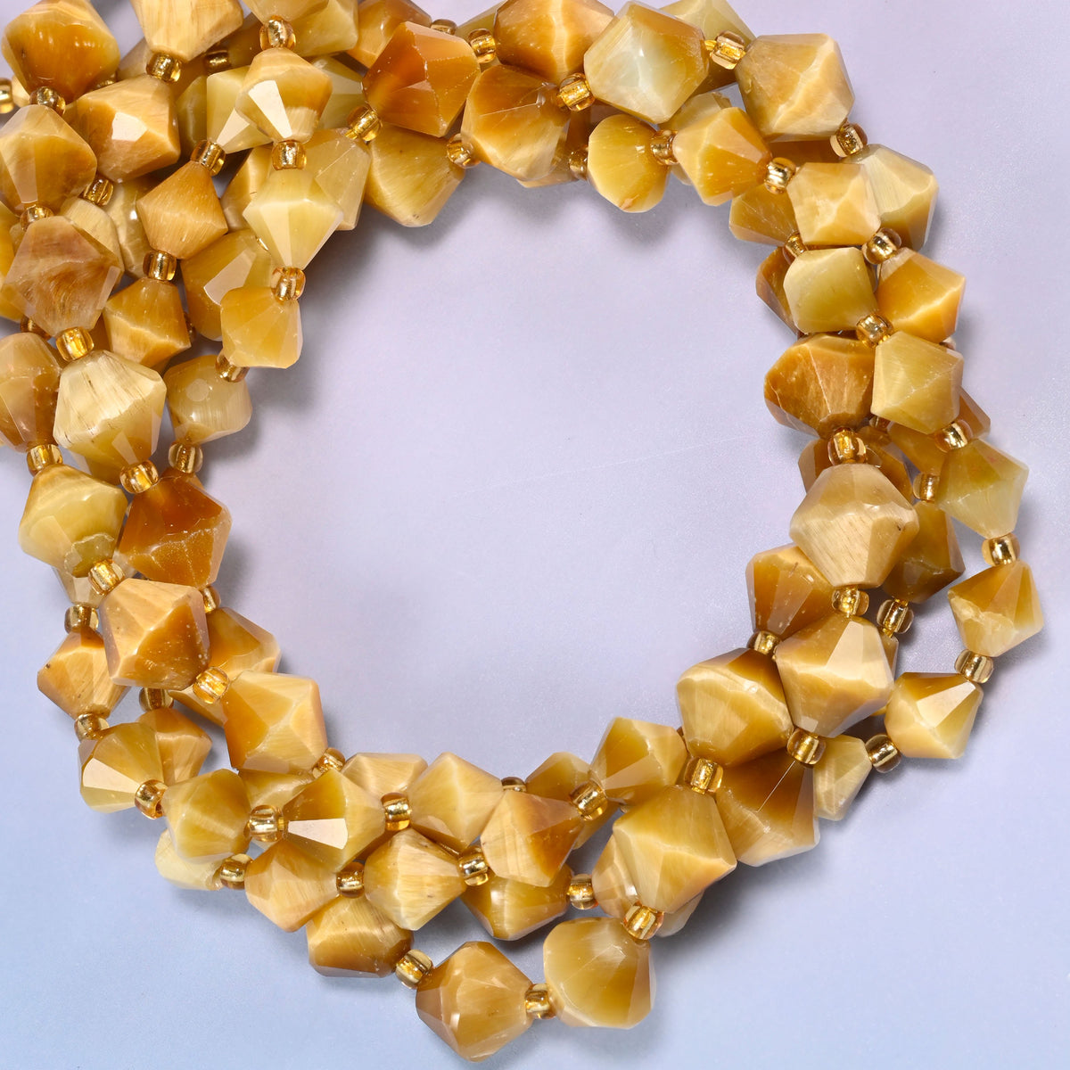 Gold tiger eye bicone beads coiled into a round ring of several strands, a soft golden shimmer traveling around the coil.