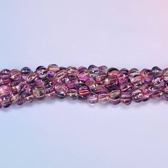 Pink blue gold pumpkin glass beads, 8mm melon rounds, strands laid in a gentle wave straight across the frame.