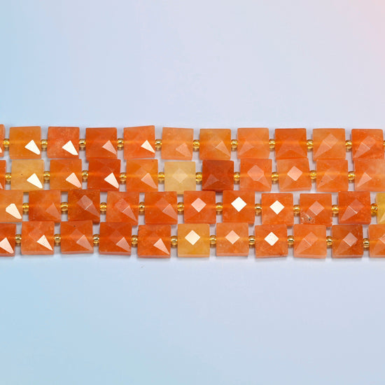 Several strands of natural red aventurine faceted flat square beads laid in straight rows