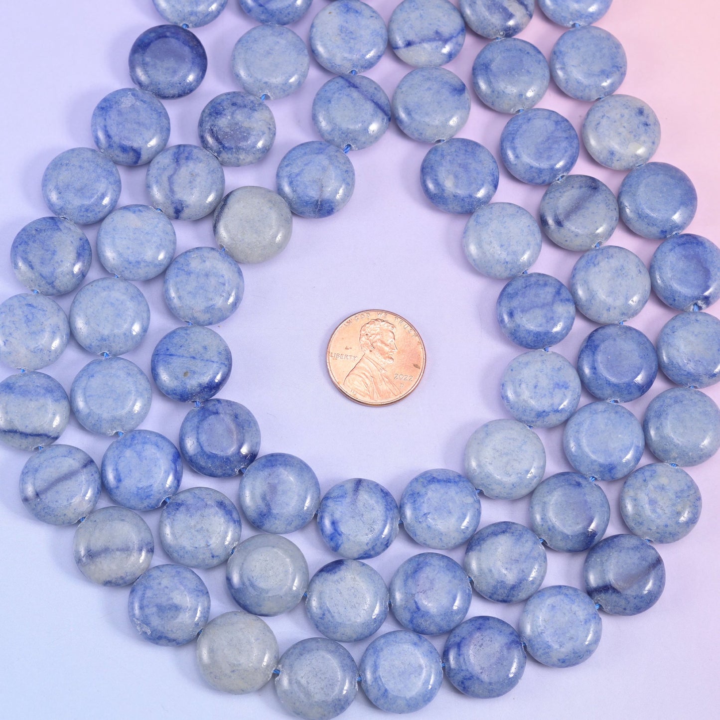 Blue aventurine coins coiled around a penny, pale sky-blue and slate tones sitting side by side