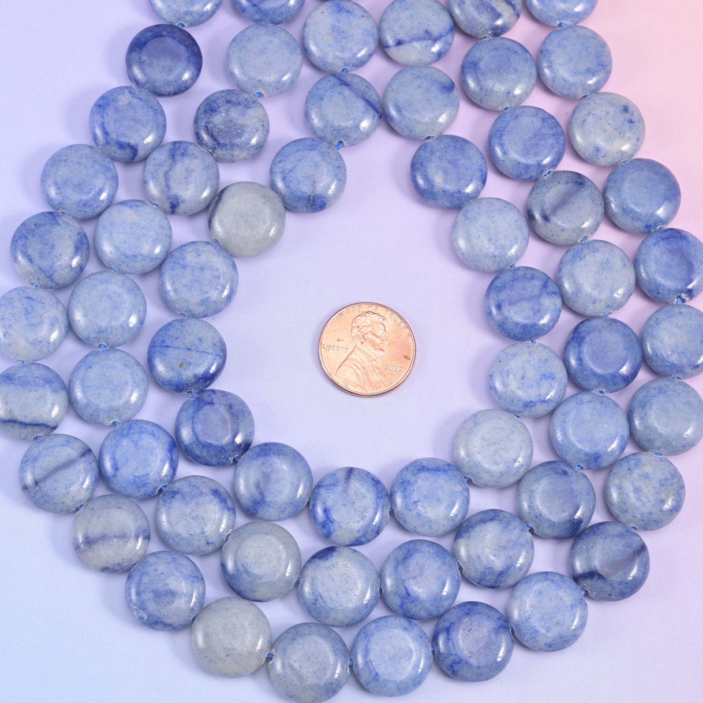 Blue aventurine coins coiled around a penny, pale sky-blue and slate tones sitting side by side