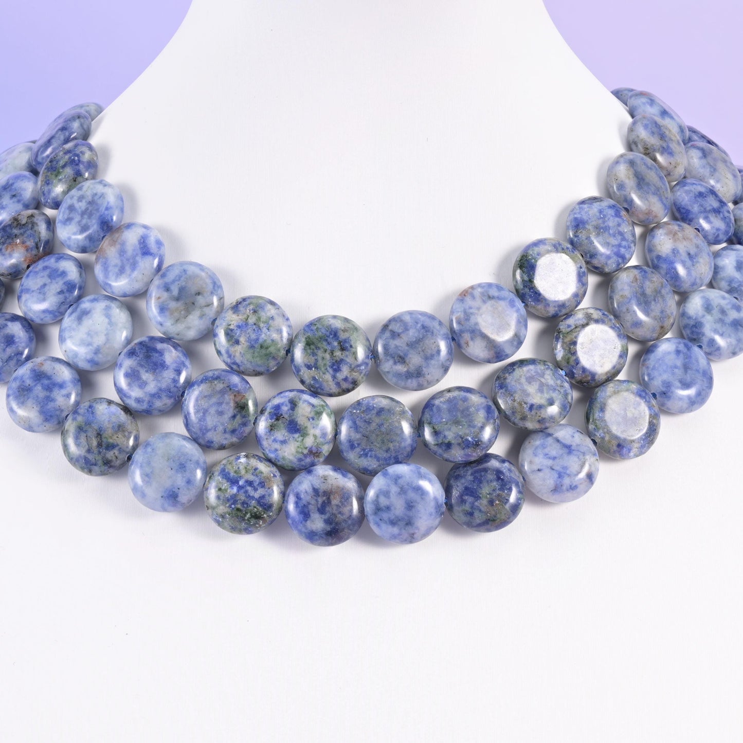 Three rows of 15mm blue spot jasper coins on a white neck form, forming a soft mottled collar