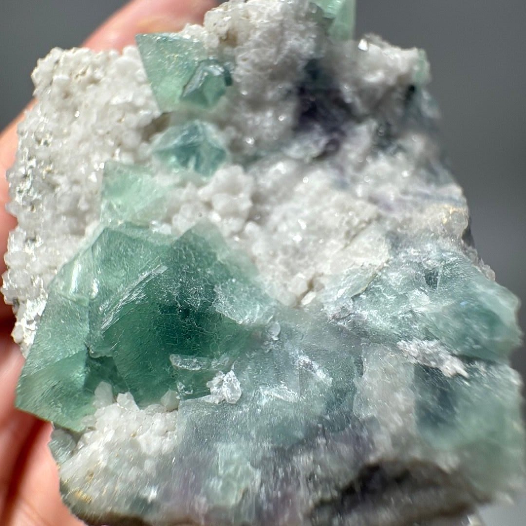 Close view of translucent green cubes rising from a crust of rounded white quartz nodules