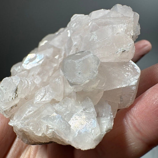 Hand-held view of the full calcite plate against a soft grey studio background