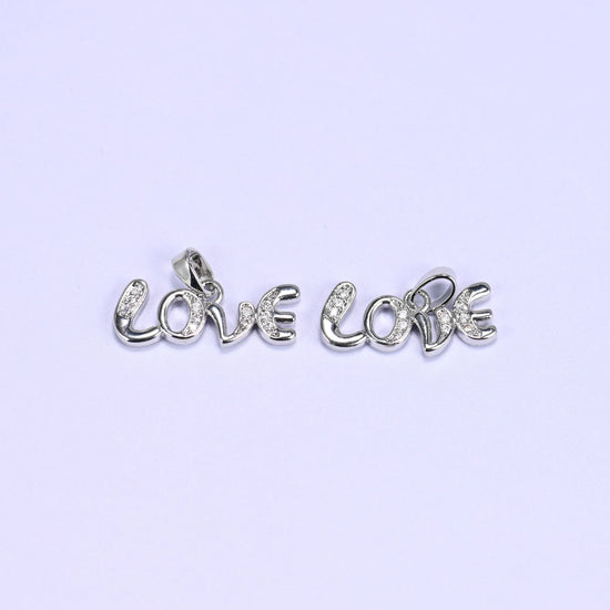 Two silver-tone Love letter zirconia charms lying side by side, the cursive Love script lined with small clear pave stones.