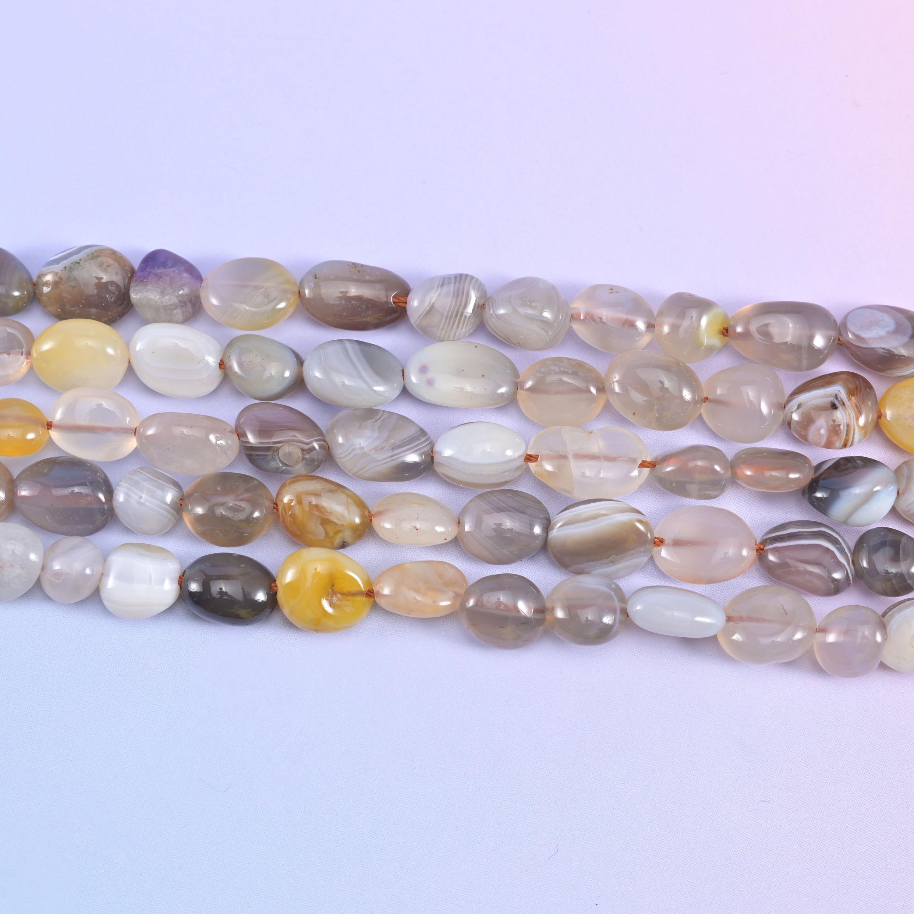 Parallel rows of smooth Botswana Agate nuggets in grey, white and butterscotch