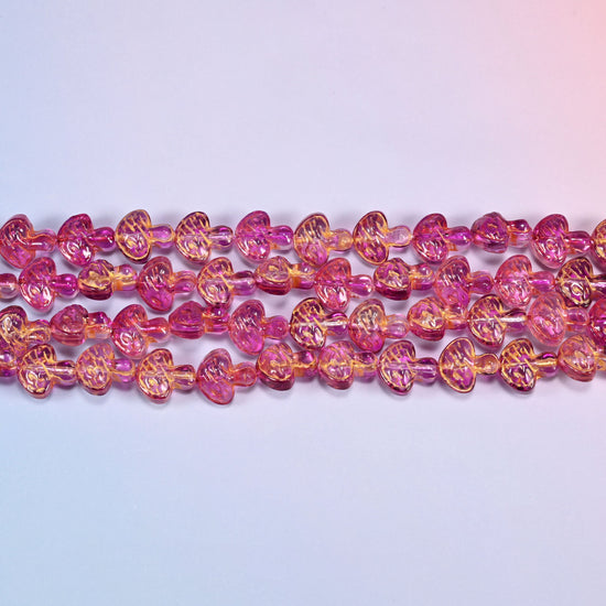 Close-up of 13x12mm pink gold flat mushroom glass beads in four horizontal rows, showing the molded gill lines.