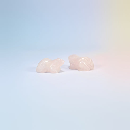 Two natural rose quartz frog carvings, light pink with folded back legs