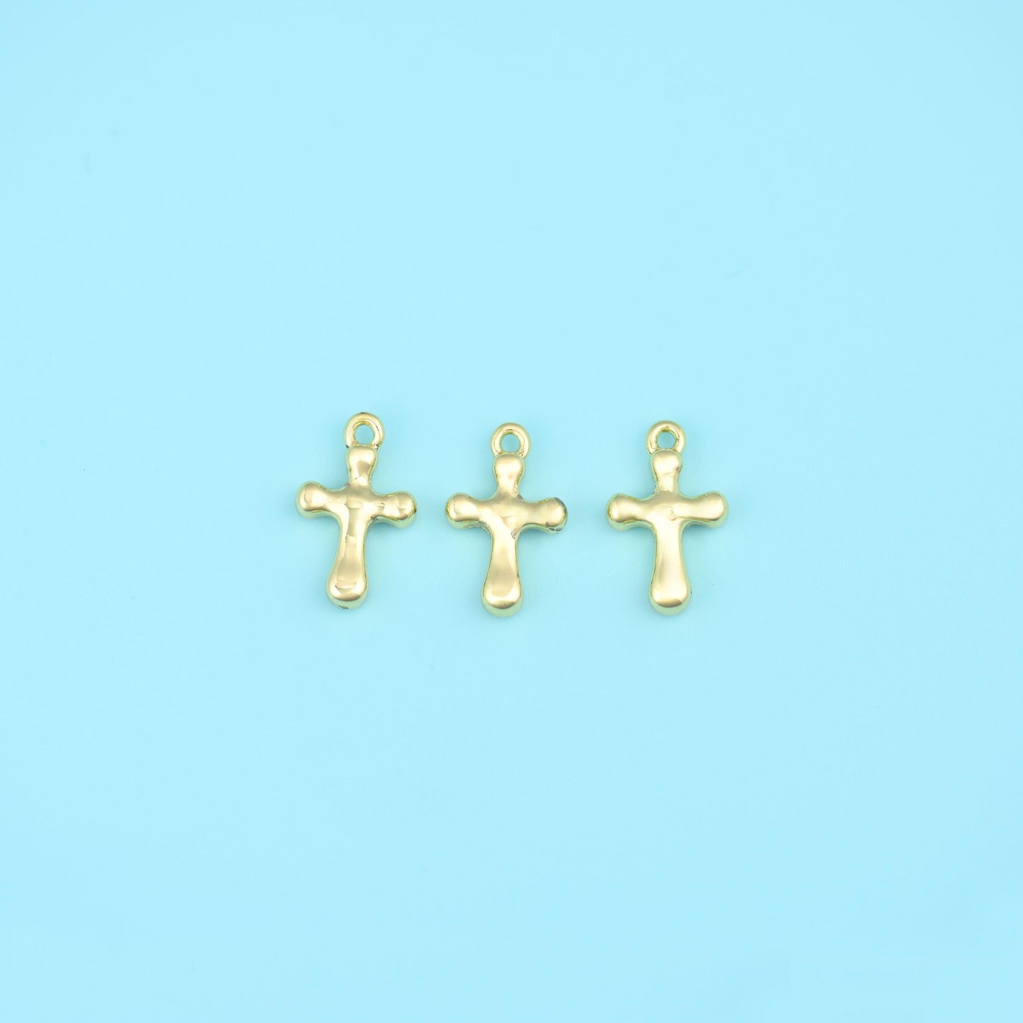 A small solid cross with softly rounded, slightly bulbed arm ends and a plain polished surface — no engraving, no stone…