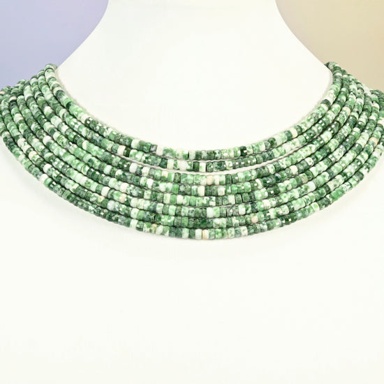 Tree agate faceted heishi disc strands arranged as a layered collar on a white display bust, green and white beads across the neck