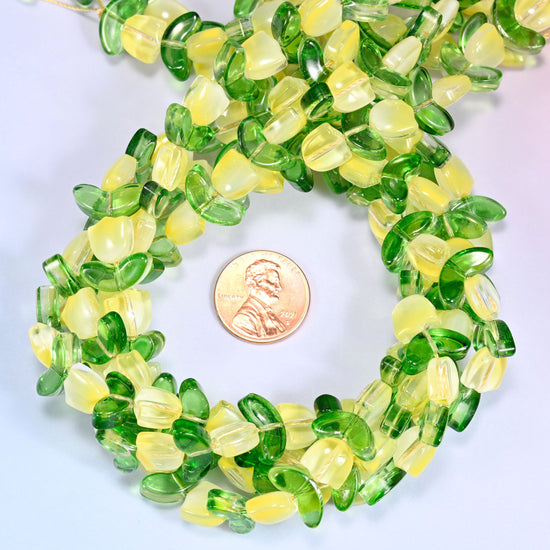 Bundled circular coil of tulip and leaf glass bead strands on a lavender background with a penny placed at the center for scale.