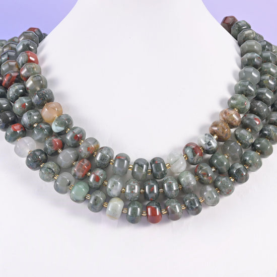 Multi-strand pumpkin rondelle necklace on a white display bust, sage green beads flecked with rust red