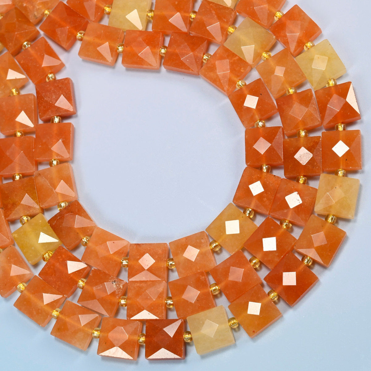 Natural red aventurine faceted flat square beads curved into an open loop, orange-red and peach orange beads