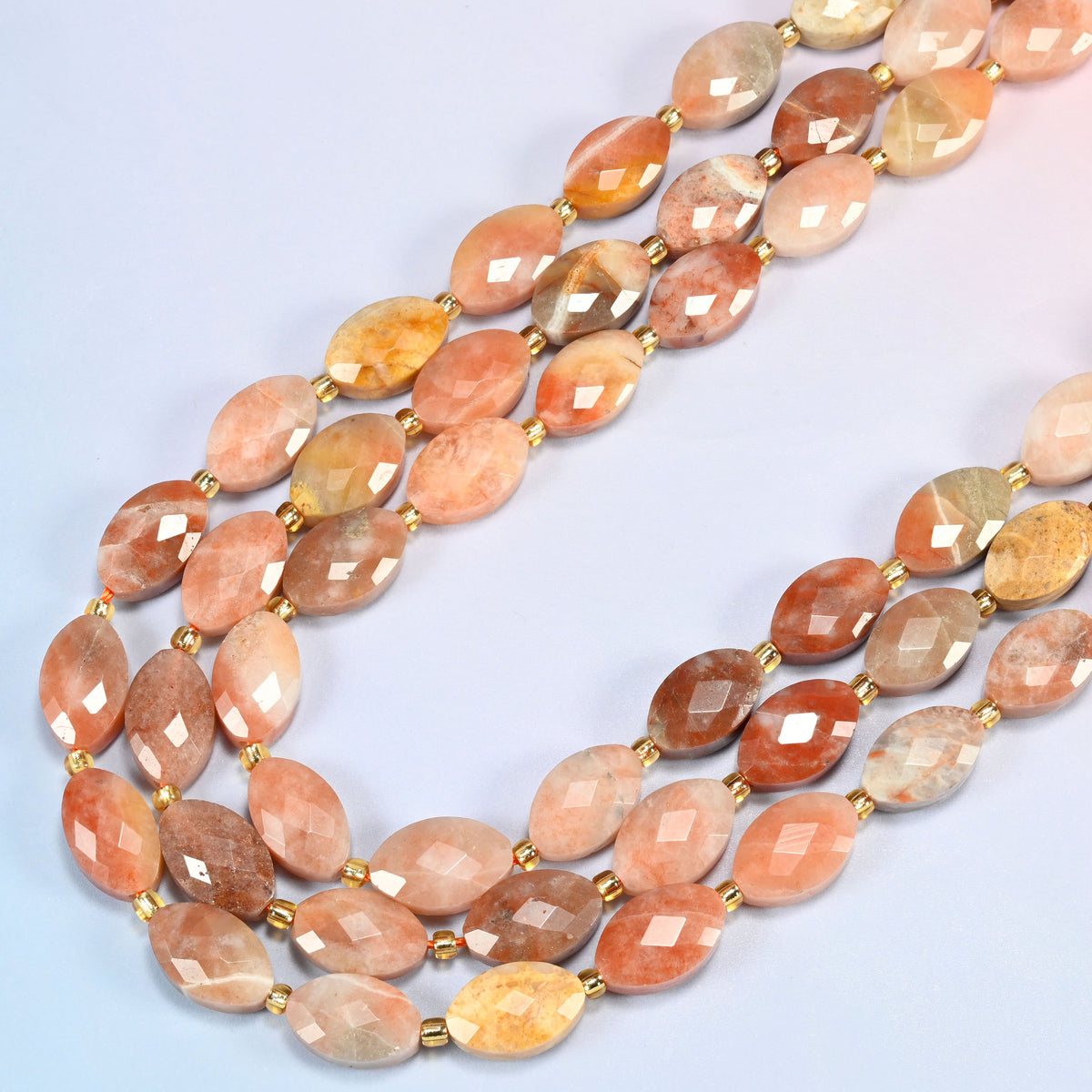 Red crazy agate faceted flat oval beads in several strands curved into a wide U, swirling peach, copper and cream