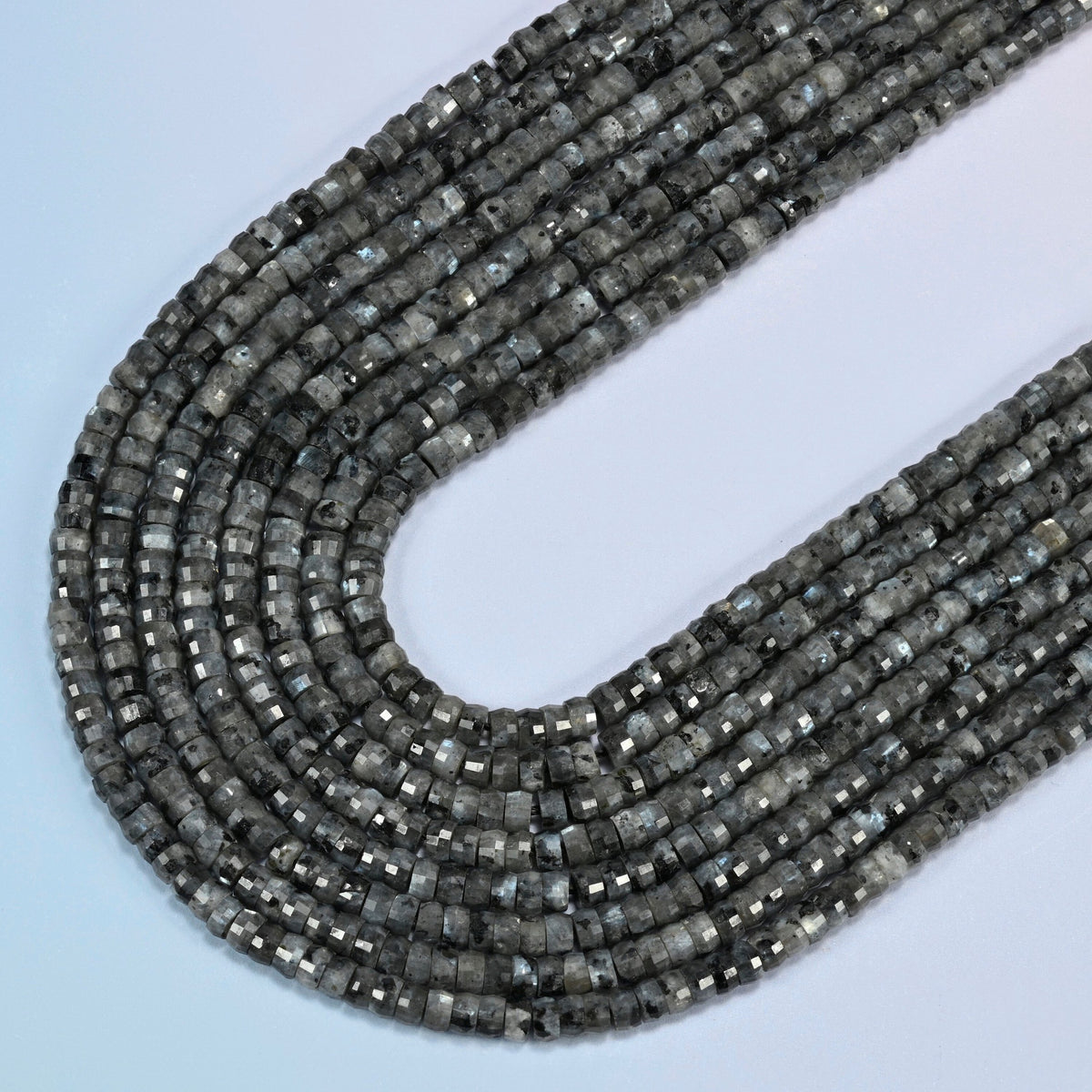 Black labradorite faceted heishi disc beads in several strands curved into a wide U, smoky dark gray stone with lighter specks