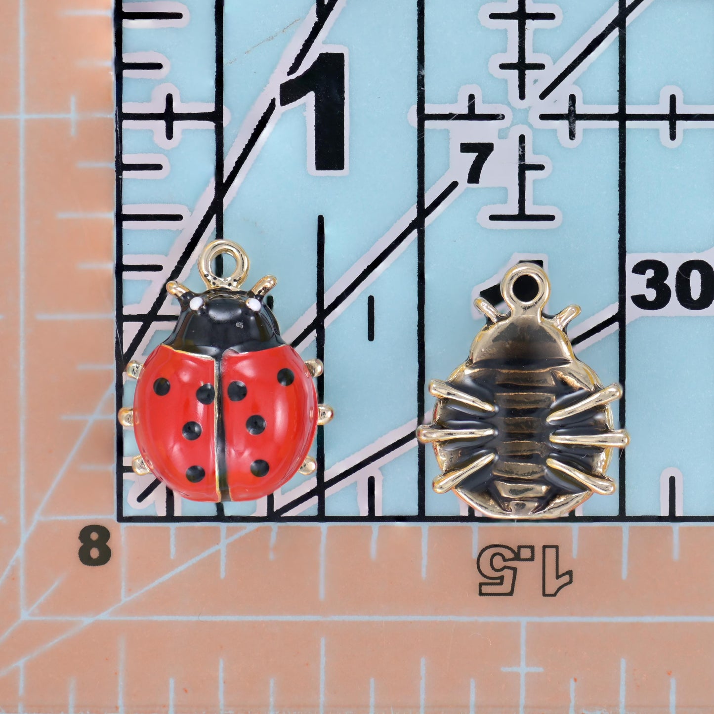 A domed red enamel shell with crisp black spots and tiny gold-tone legs, backed by a textured antique gold-tone reverse