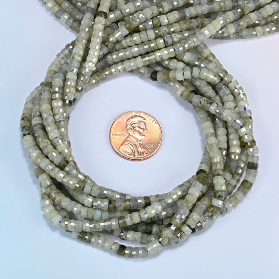 White labradorite faceted heishi disc beads 2x4mm coiled in a loop around a US penny for scale, close-up of the faceted disc shape