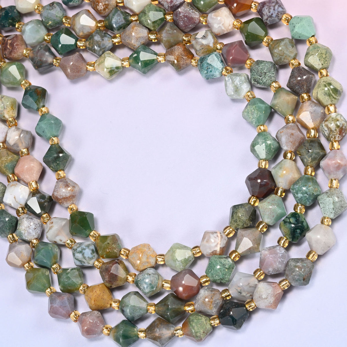 Indian Agate faceted bicone beads 8mm with gold-tone spacers, strand coiled into a wide circle, close-up of the multicolor beads