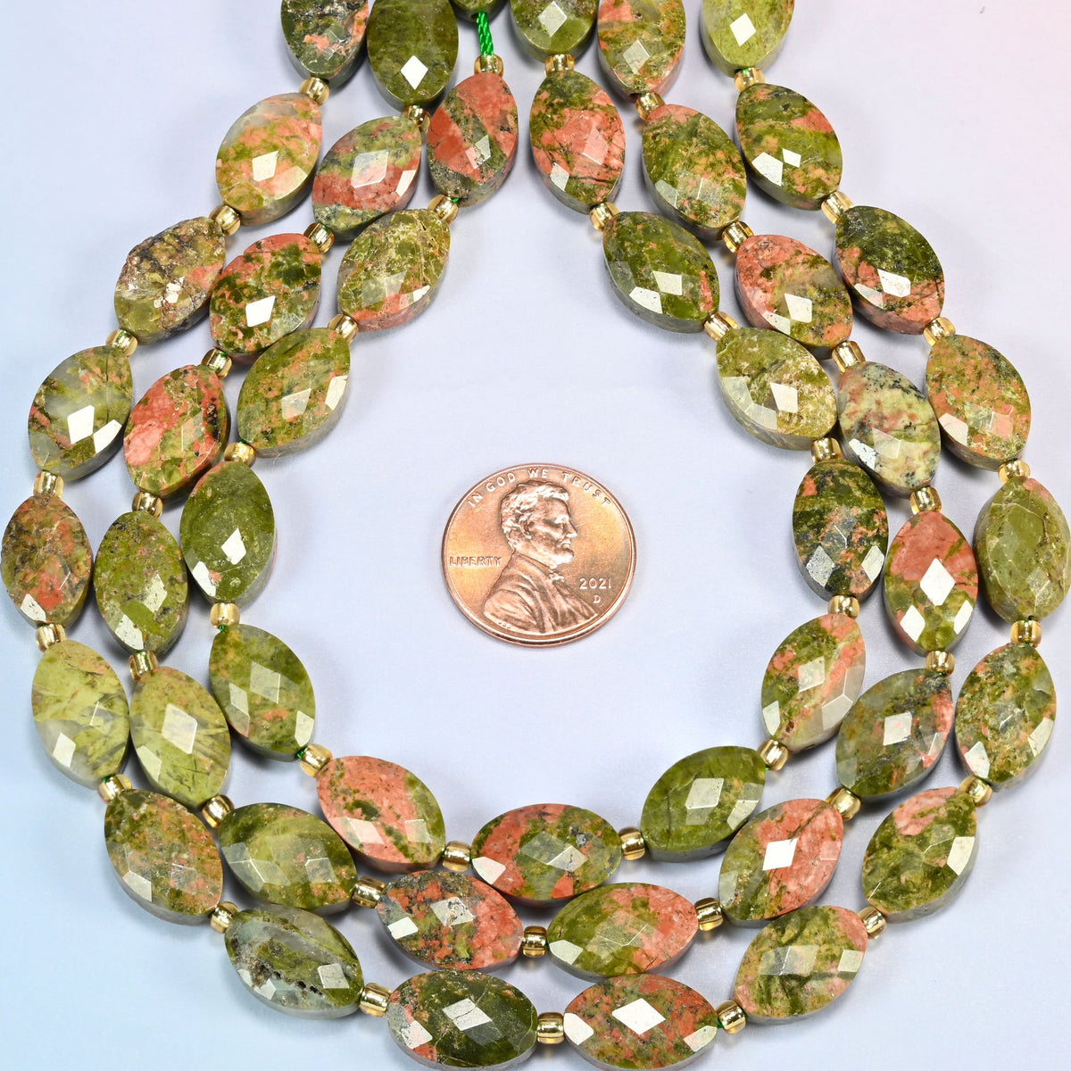 Unakite faceted flat oval strands formed into a teardrop loop around a US penny for scale