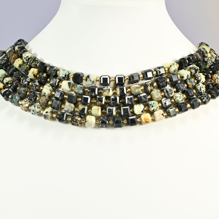 Old African howlite faceted cube strands arranged as a layered collar on a white display bust, black and cream speckled beads across the neck