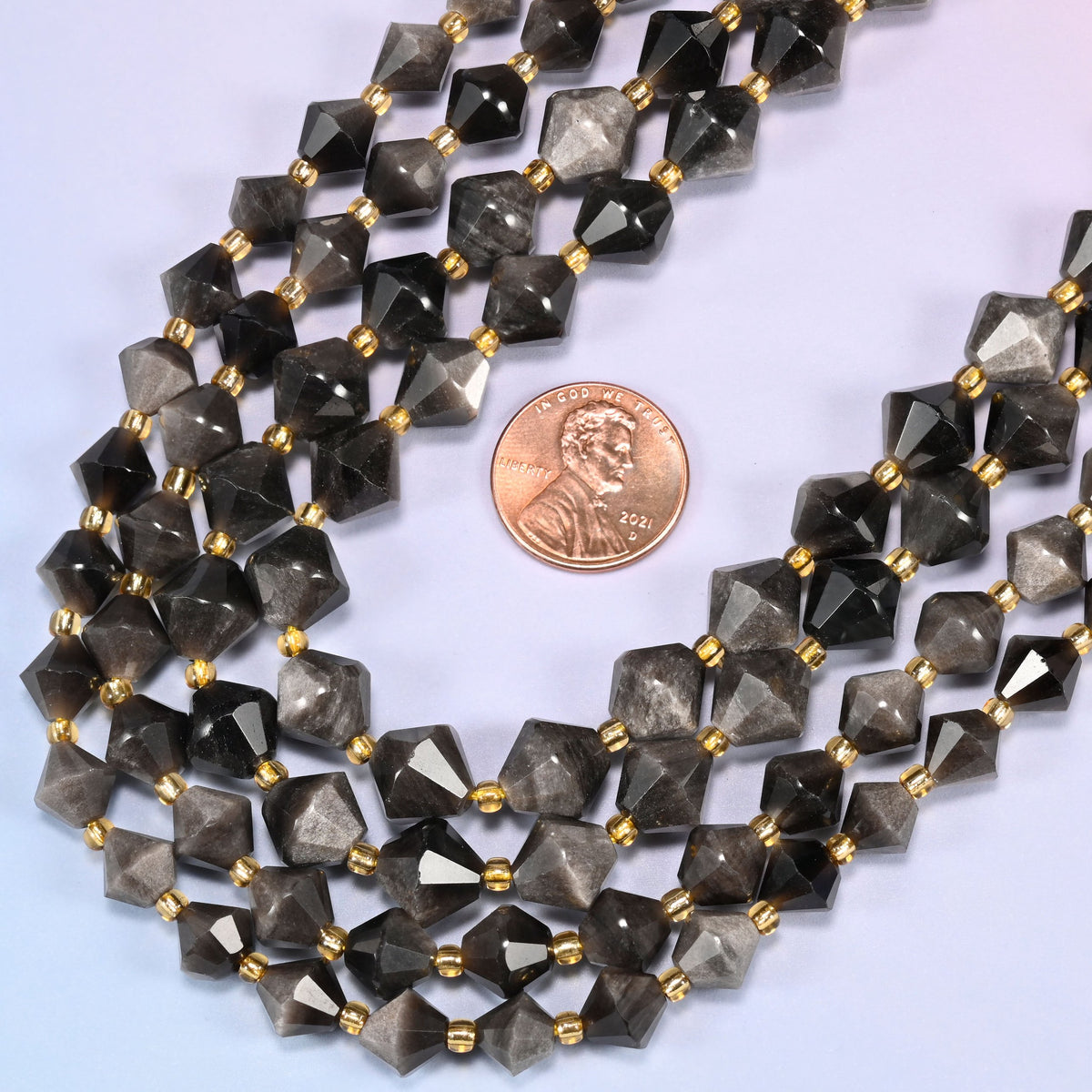Silver obsidian bicone beads in a wide curve, available in 8mm and 10mm, with a gold-tone spacer between each bead.
