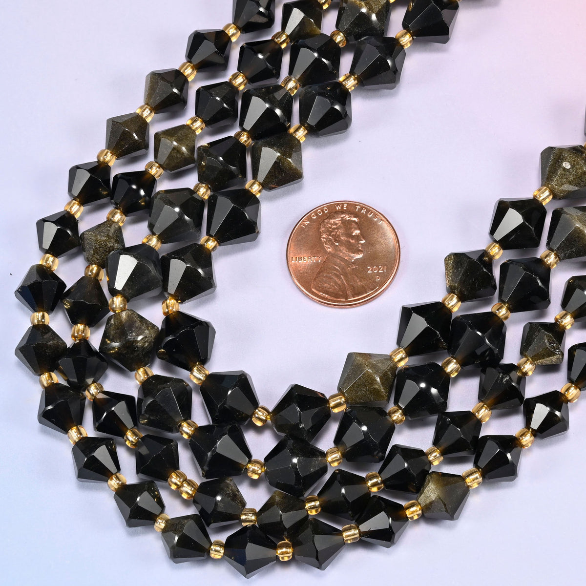 Gold obsidian bicone beads in a wide curve, available in 8mm and 10mm, with a gold-tone spacer between each bead.