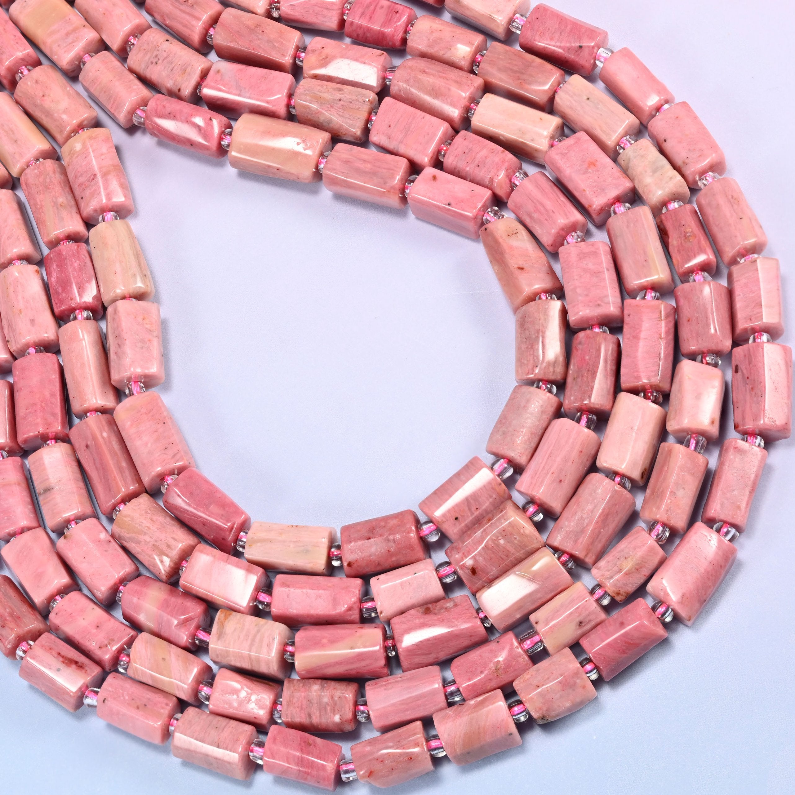 Pink Rhodonite faceted tube beads coiled in a full loop, a 15.5 inch strand holding roughly 30 beads