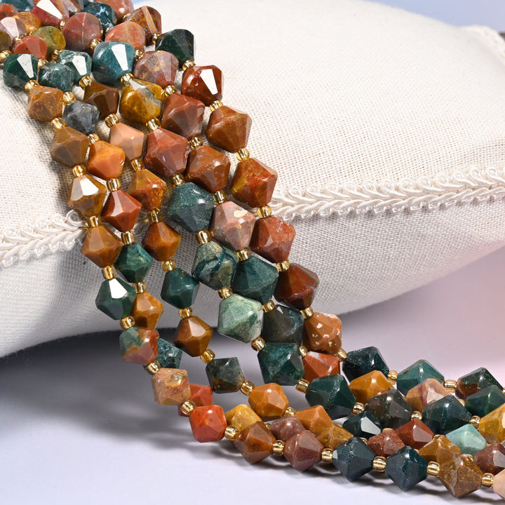 Ocean agate faceted bicone beads strung with gold glass spacers, several strands draped over a white linen cushion.
