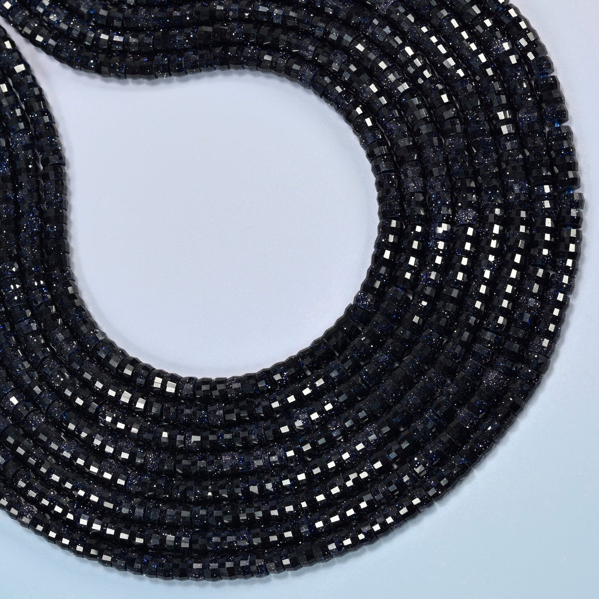 Blue sandstone faceted heishi disc beads curved into an open loop, dark blue beads with silver-blue glitter