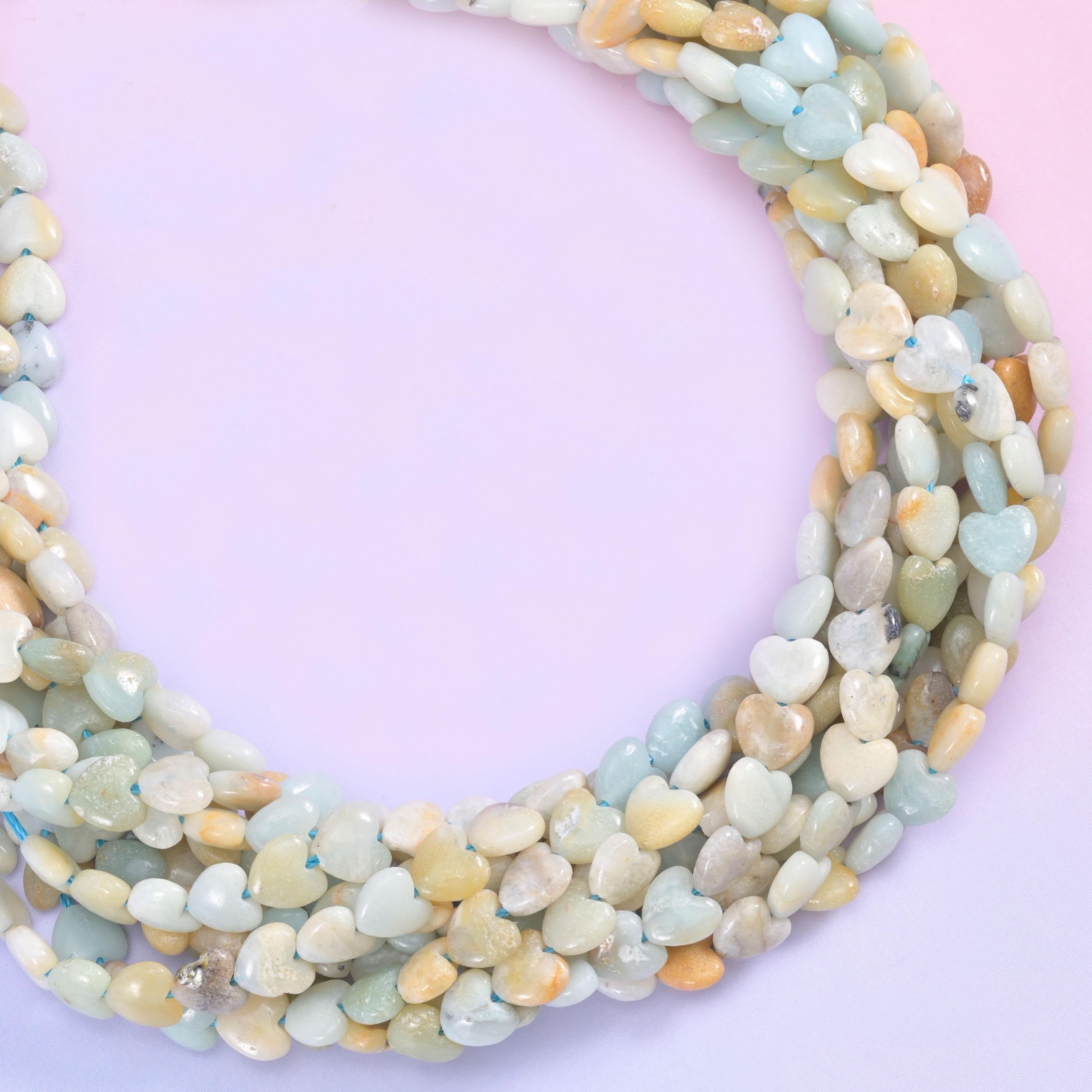 Pale seafoam green, cream, chalky white and sandy mustard tones mixed along the same strand, small puffed hearts