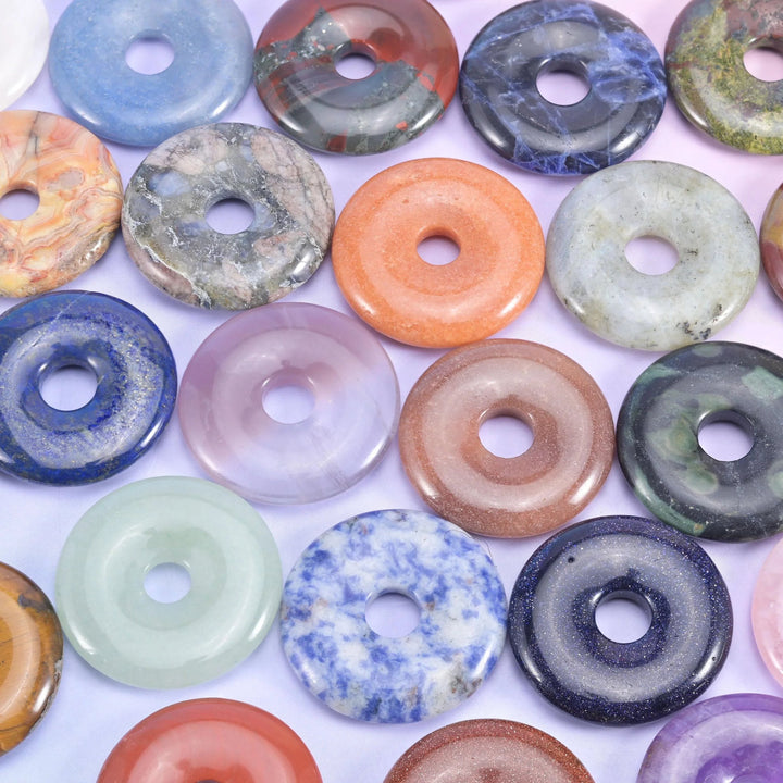 Close pile of 30mm stone donuts in mixed colours, from lapis blue and rose quartz to orange jasper