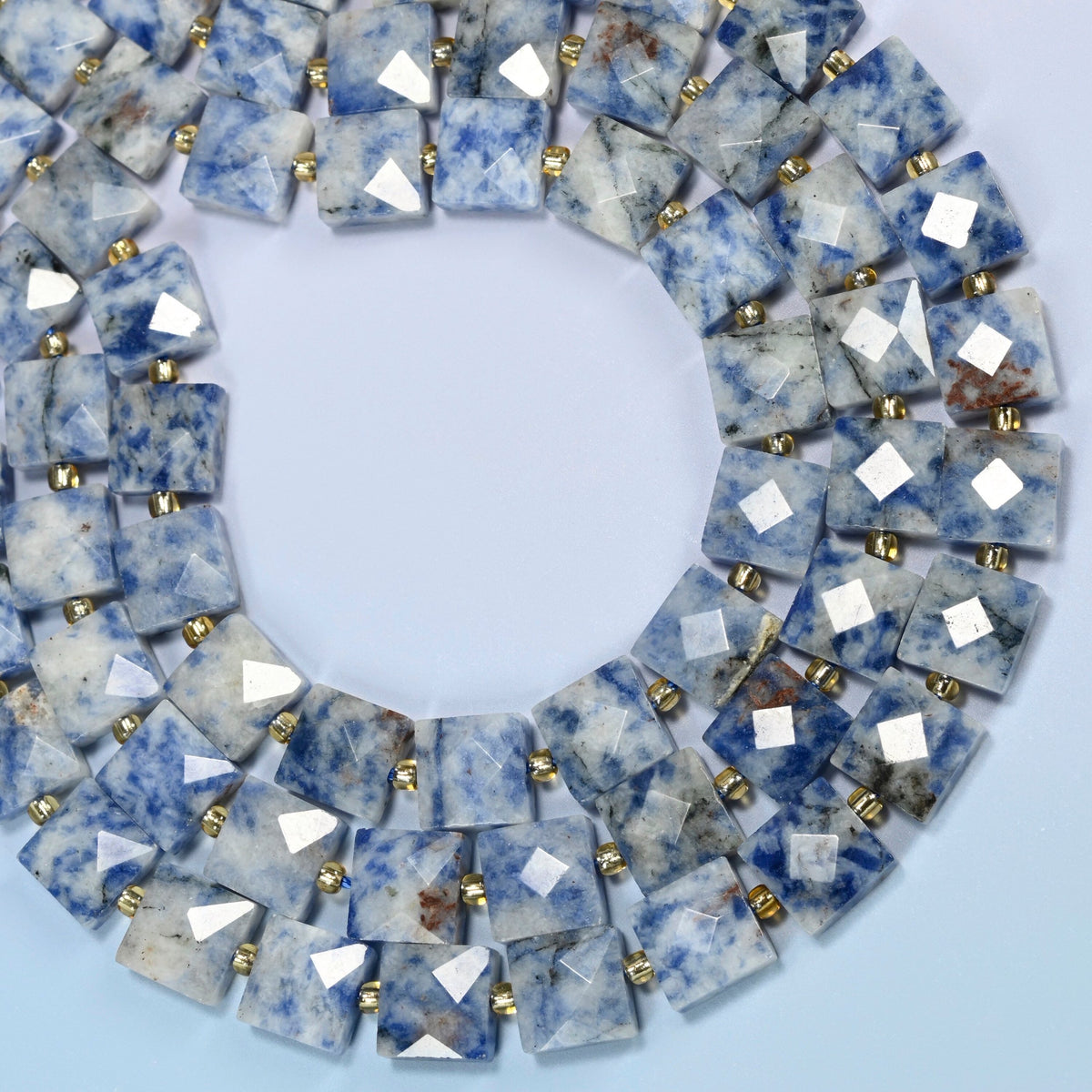 Natural blue spot jasper faceted flat square beads curved into an open loop, white and light gray beads with blue spots