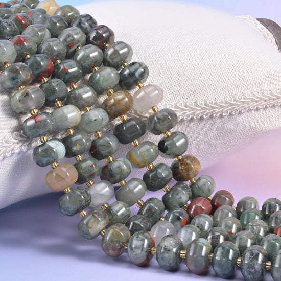 African bloodstone pumpkin rondelle strands on a cream cushion, ribbed grey-green beads with gold spacers