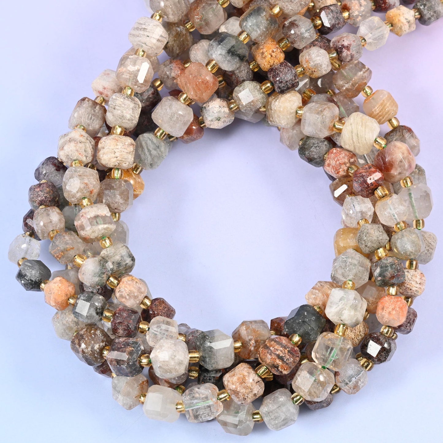 Milky, part-clear quartz cubes with rust, tan and grey phantom layers suspended inside like sediment lines, faceted at the corners so you see straight into the stone.