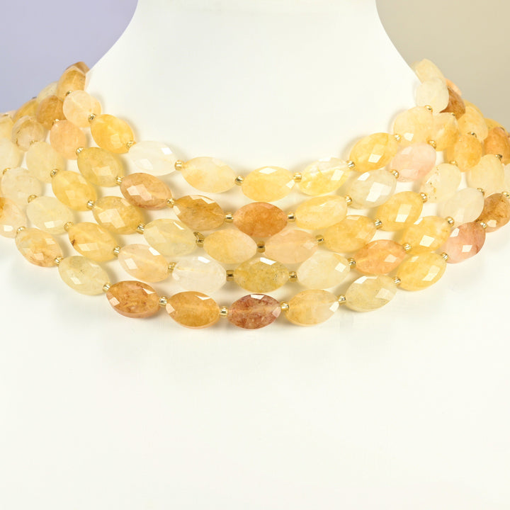 Golden healer quartz faceted flat oval strands arranged as a layered collar on a white display bust, golden yellow beads across the neck