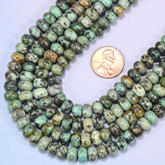 Rows of African Howlite rondelle beads laid straight on a lavender surface, showing the natural stone color variation.