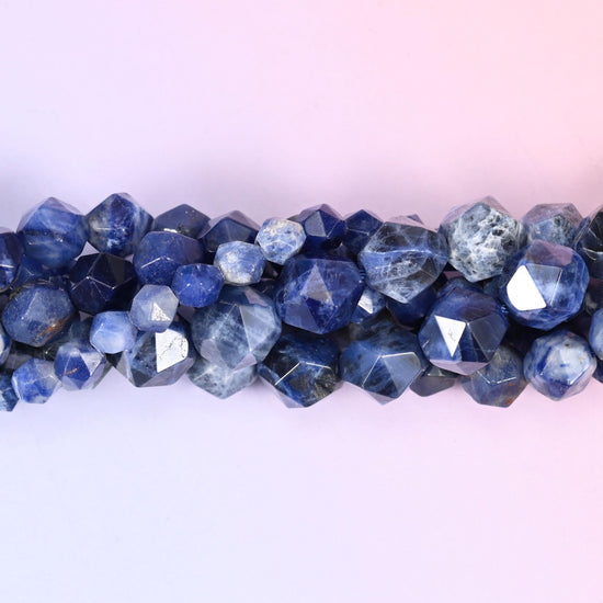 Deep royal blue marbled with chalky white and soft grey, cut into a geometric star pattern so each round is covered in broad flat panels that flash light as the strand turns. Three sizes to work with.