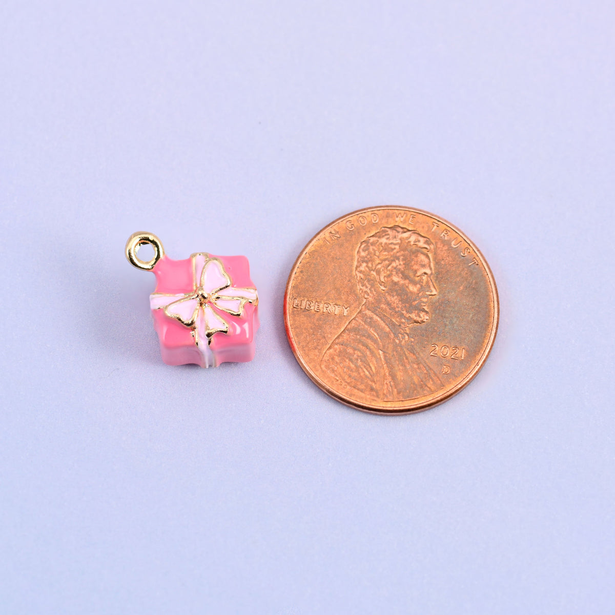 Pink gift box charm shown at actual size, a cube of roughly 9.5mm.
