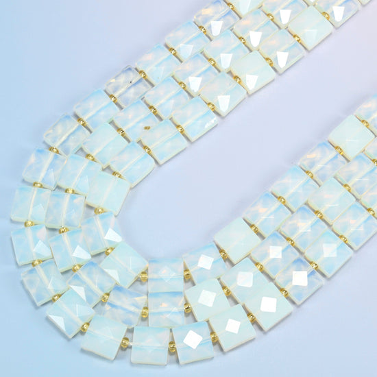 Opalite faceted flat square beads in several strands curved into a wide U, translucent milky white glass with a soft blue glow