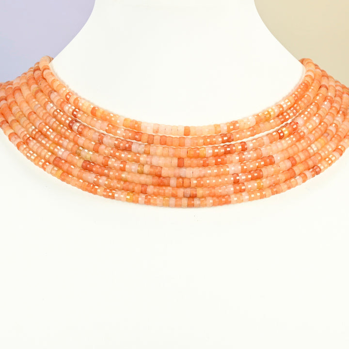 Red aventurine faceted heishi disc strands arranged as a layered collar on a white display bust, orange-red beads across the neck