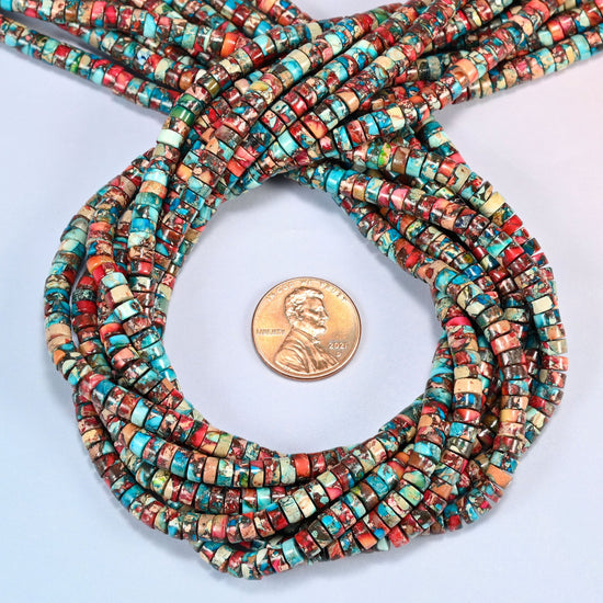 Dyed red blue sea sediment jasper heishi disc beads 2x4mm coiled in a loop around a US penny for scale, close-up of the thin disc shape