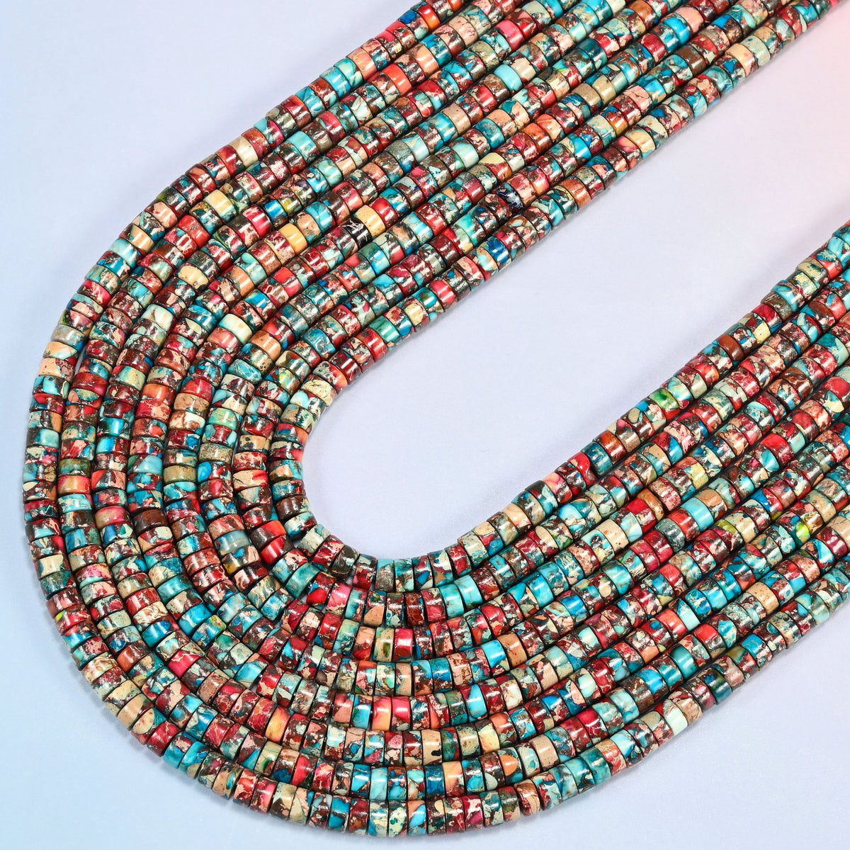 Dyed red blue sea sediment jasper heishi disc beads 2x4mm in several strands curved into a wide U, turquoise, brick red and cream marbled discs