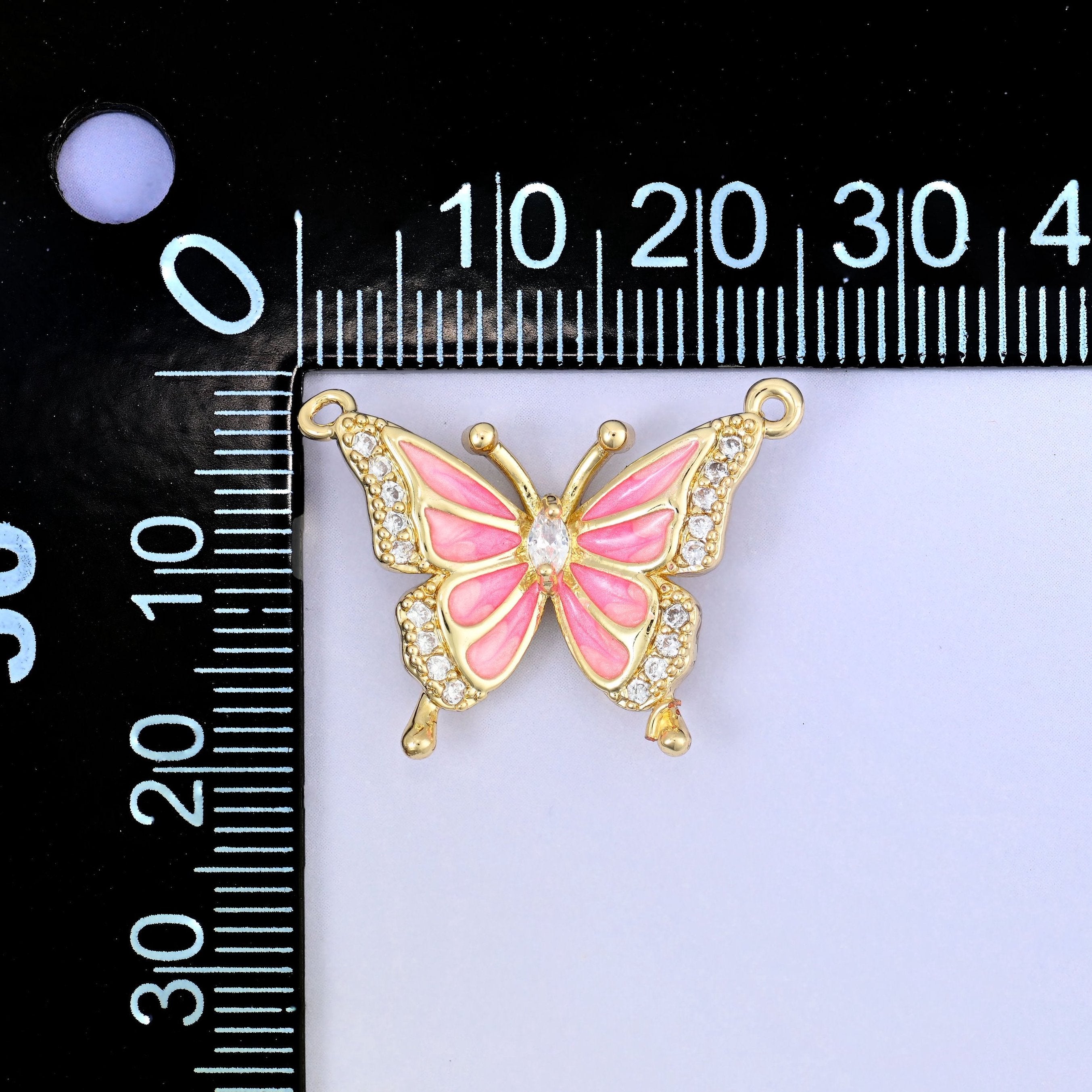Open gold wings filled with soft blush pink enamel and outlined in clear zircon