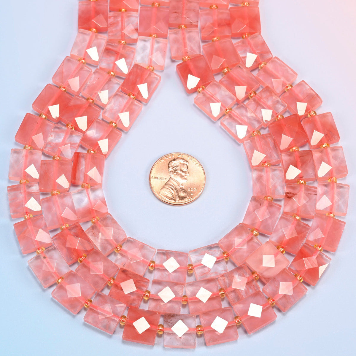 Melon quartz faceted flat square strands formed into a teardrop loop around a US penny for scale