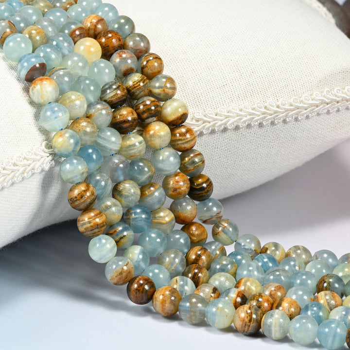 Blue Calcite smooth round beads draped in a soft curve, soft blue stone banded with warm tan and gold brown