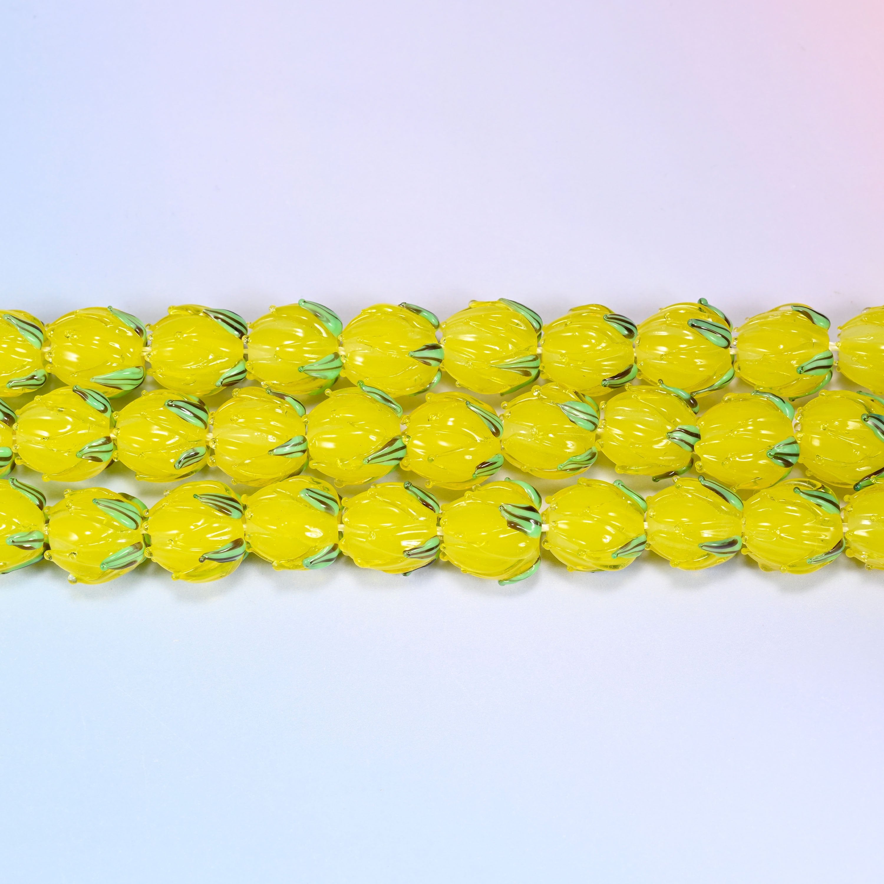 Yellow tulip bud glass beads in translucent yellow with a green leaf detail at the base