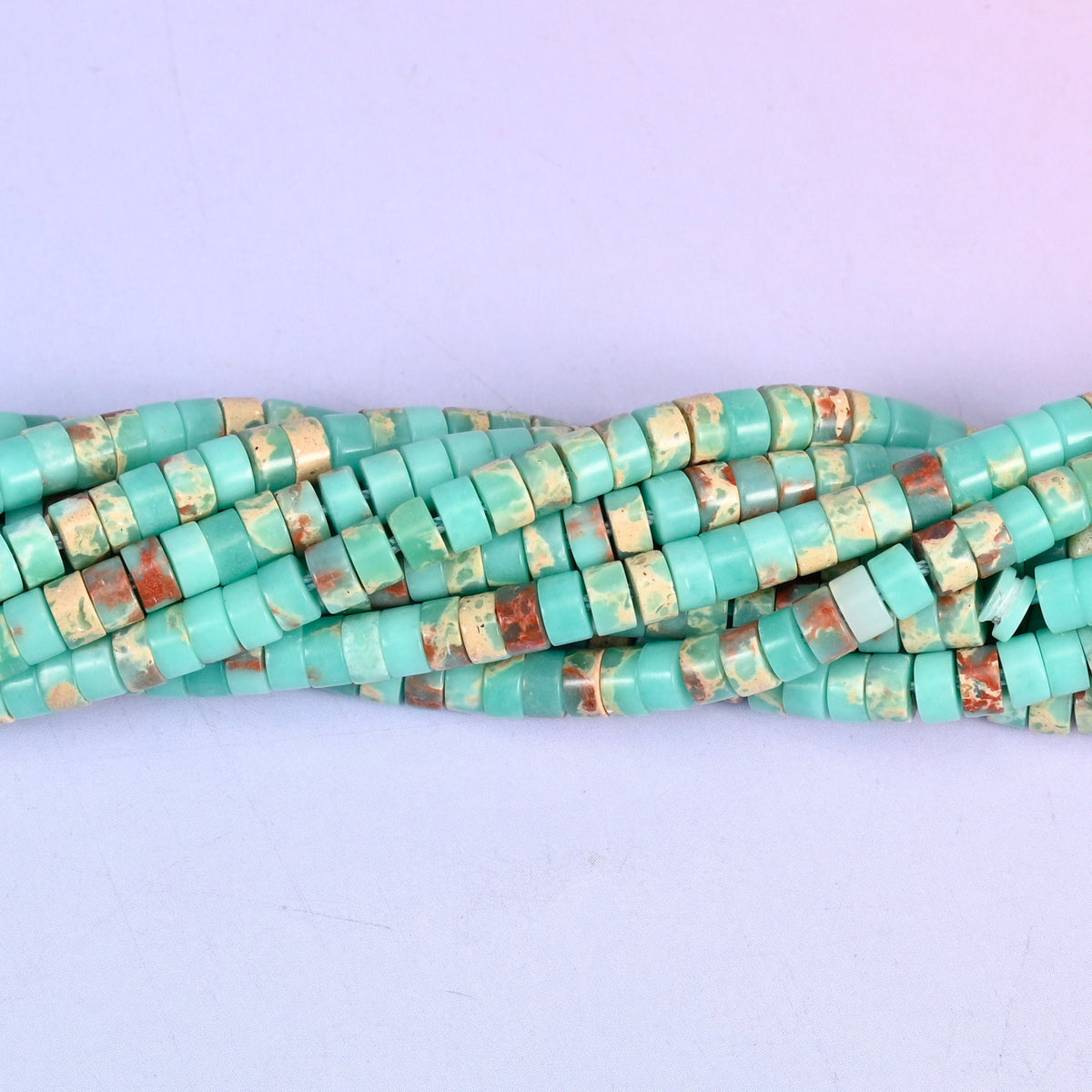 Turquoise-green mottled with rust red and cream, so each little disc looks like a slice cut through desert stone. Around a hundred and eighty to the strand.
