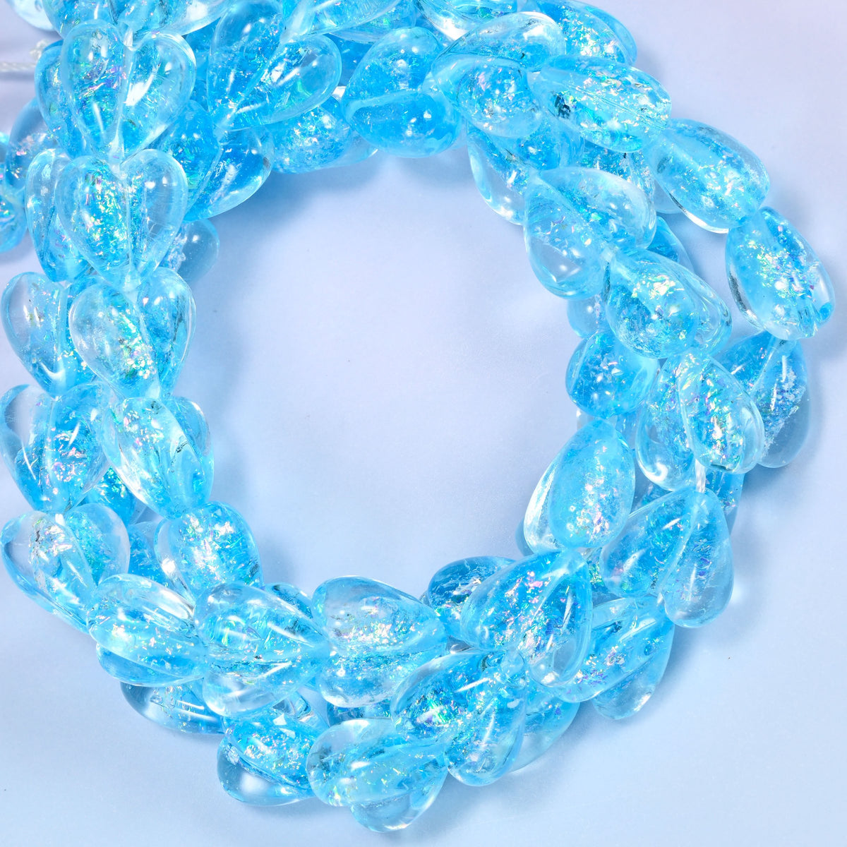 Iridescent light blue heart glass beads coiled into a ring, the full 11.5 inch strand of 24 hearts
