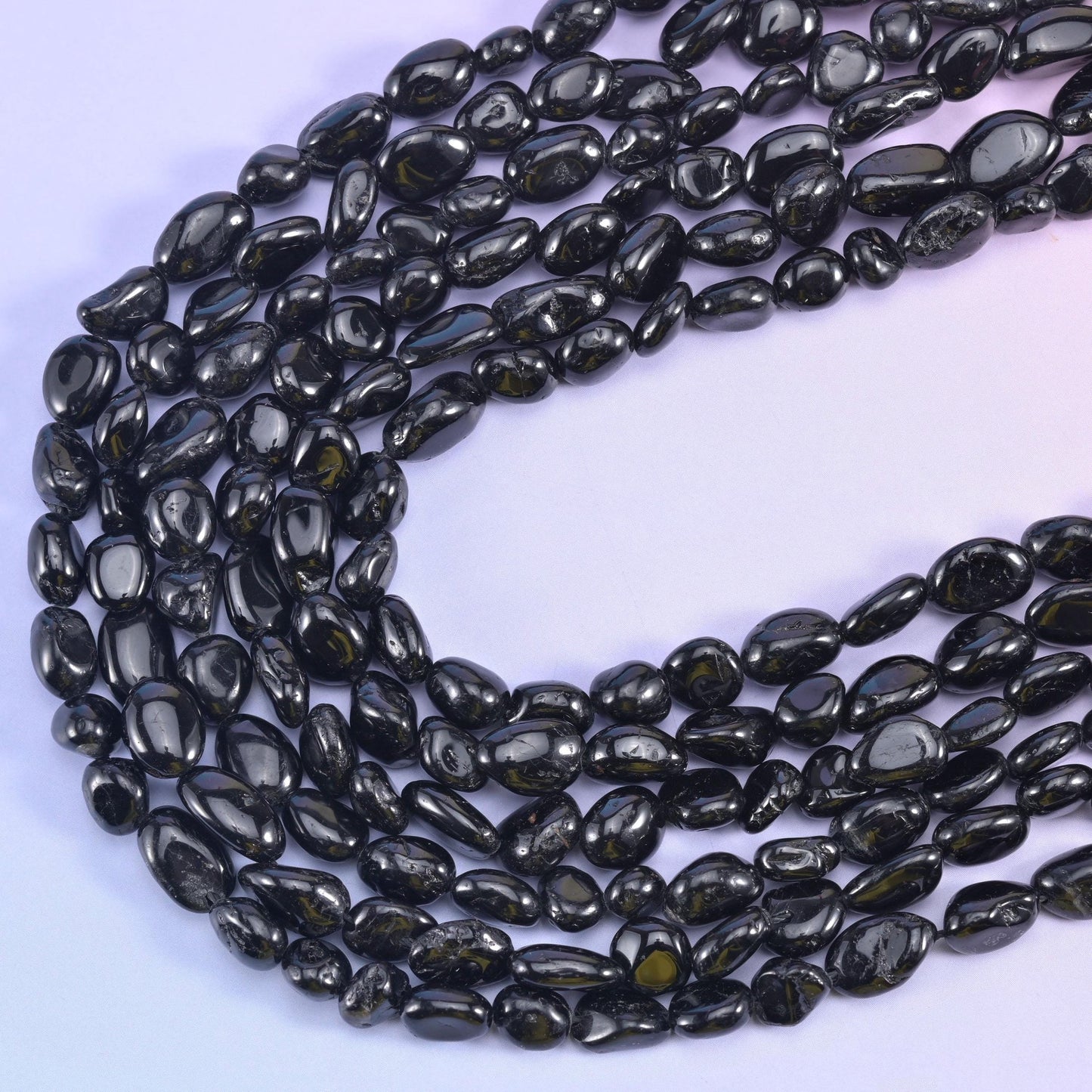 Black tourmaline strands curving in a U shape, tumbled nuggets in mixed sizes