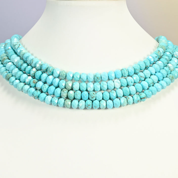 Dyed light blue howlite faceted rondelle strands arranged as a layered collar on a white display bust, veined turquoise across the neck
